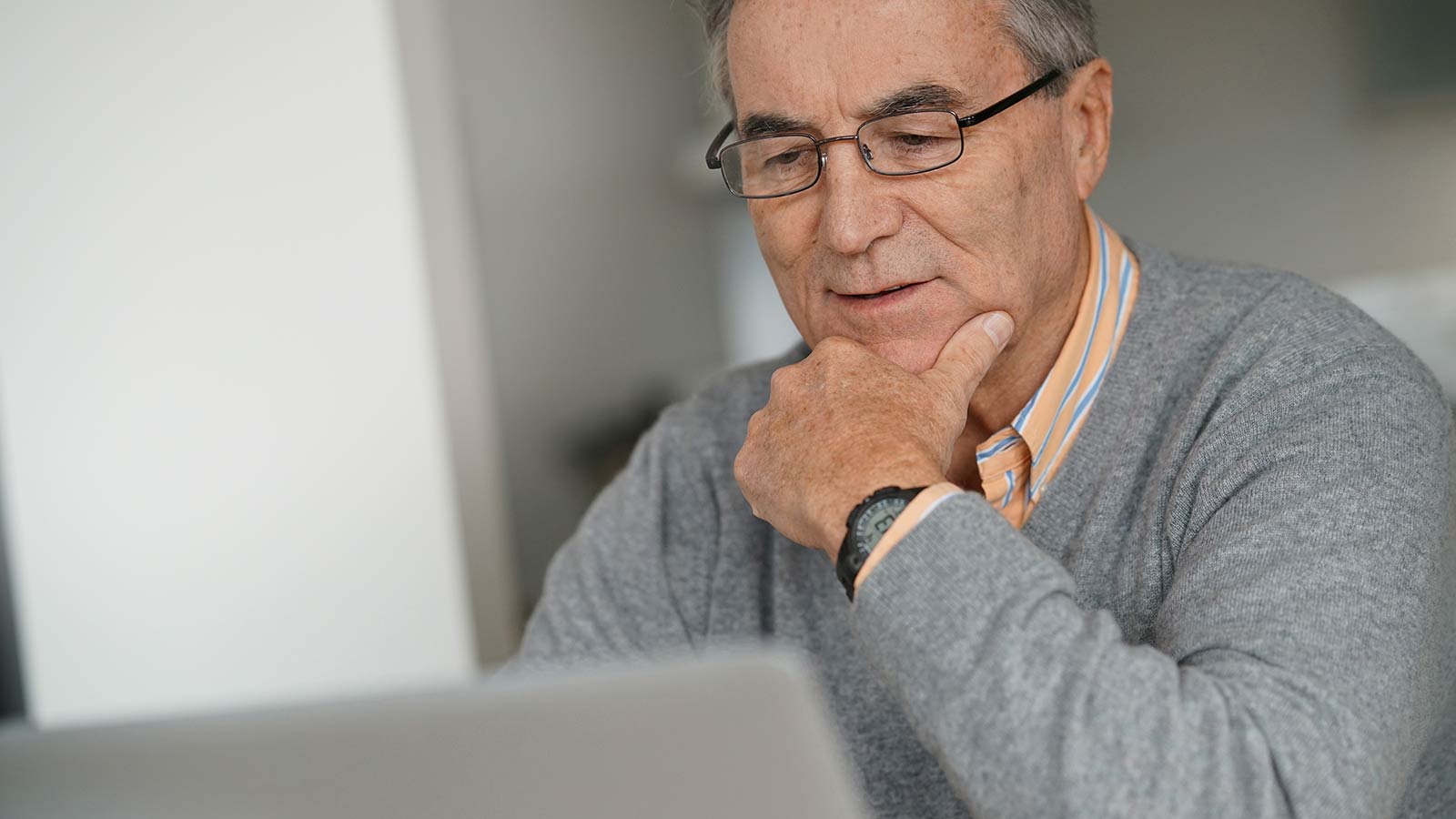 Ældre mand sidder ved bærbar computer