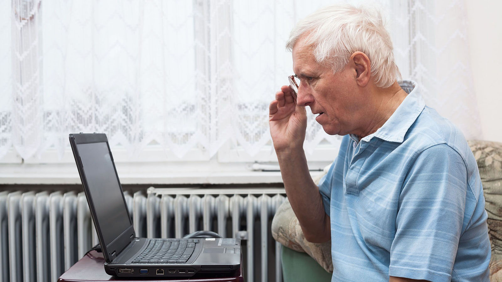 Ældre mand sidder foran en bærbar computer